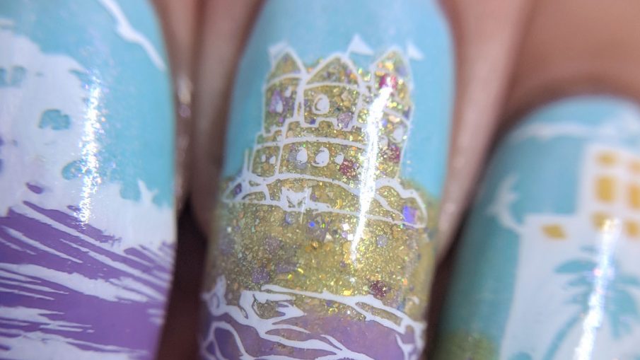Day at the Beach 2.0 - Hermit Werds - nail art of a lilac ocean and glittery sand with waves, sandcastle, and beach-y city.