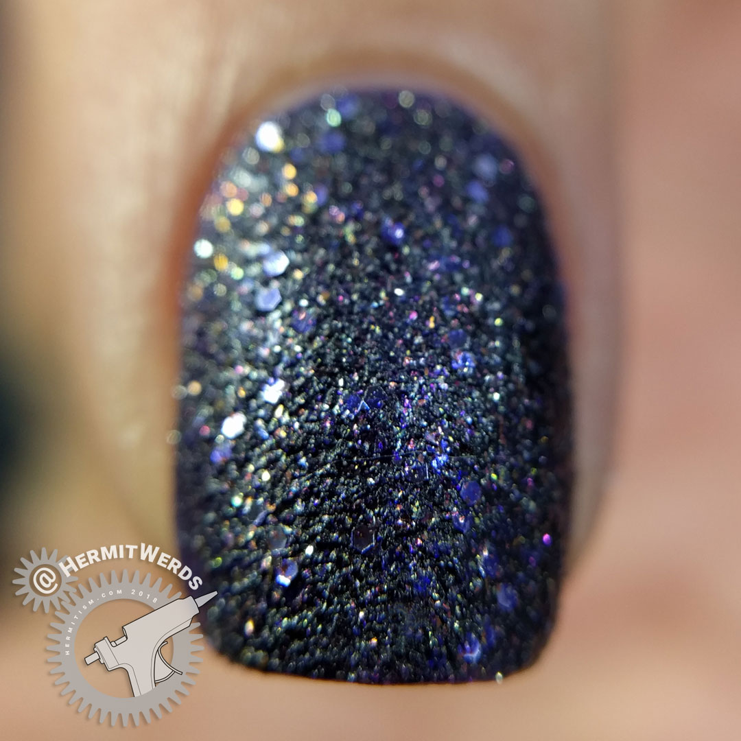 L'oreal's "Sexy in Sequins" - Hermit Werds - macro of a dark purple texture polish with gold glimmers.