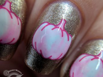 Glam-kin - Hermit Werds - nail art of a white pumpkin stamping tinted a little bit pink on a glitzy golden background