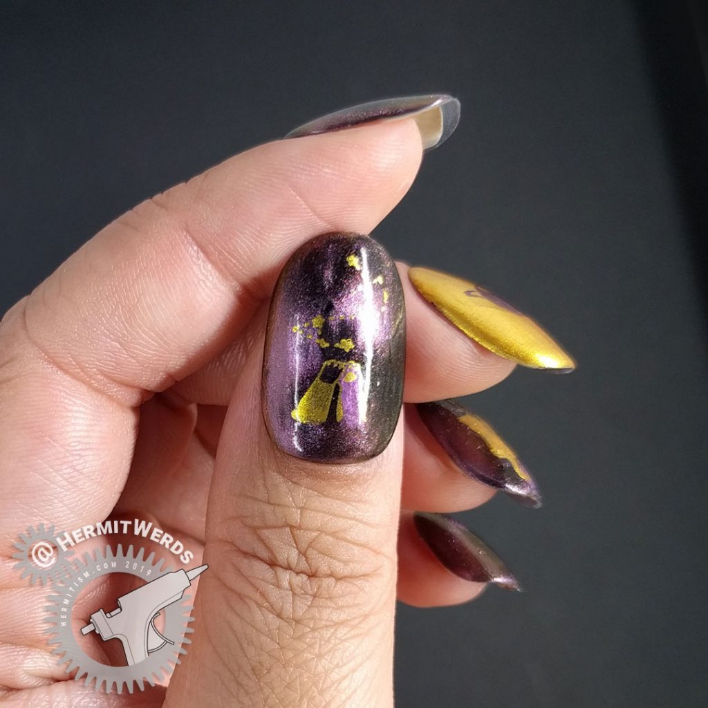 Purple/pink magnetic polish with golden space cats stamped on top.