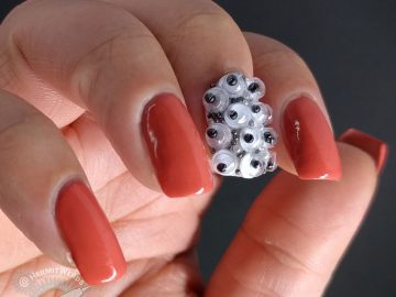 Crab apple colored nail art with googly eyes and a wee monster on the thumb.