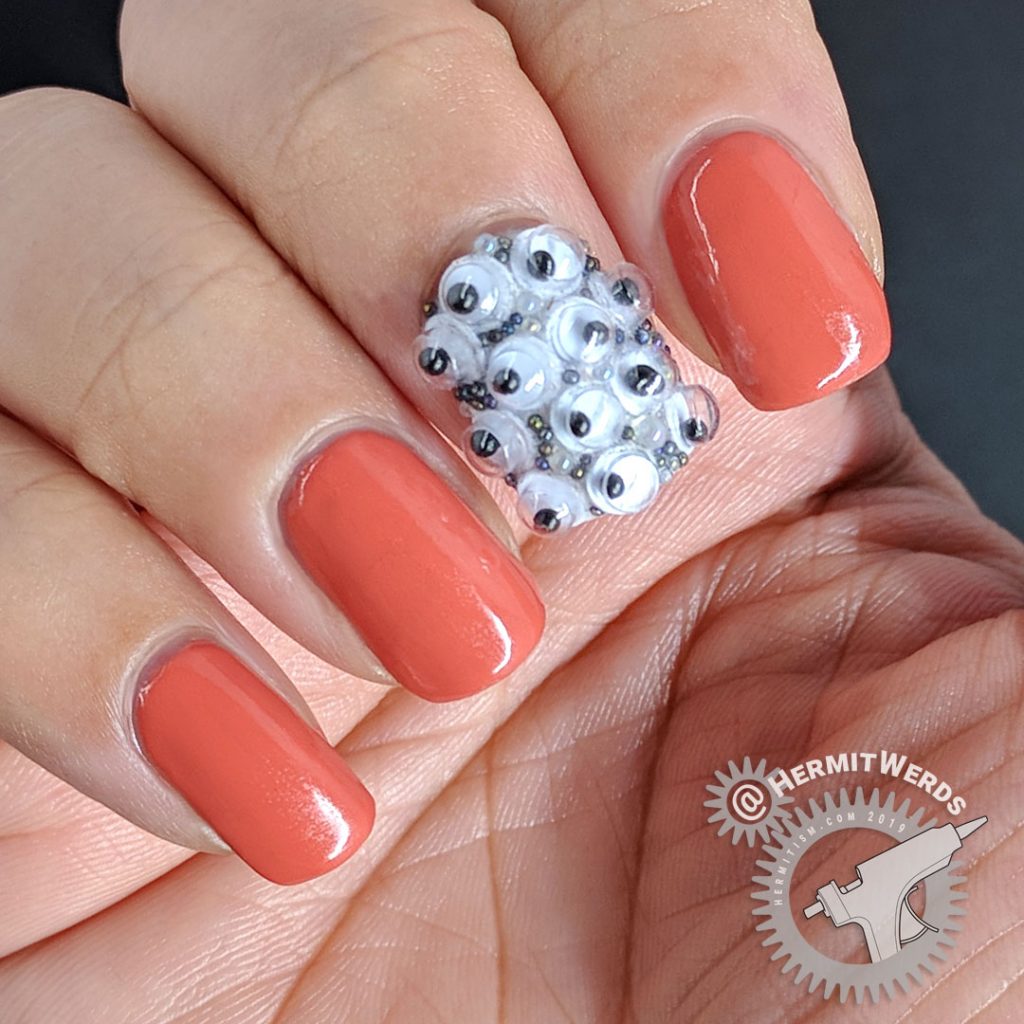 Crab apple colored nail art with googly eyes and a wee monster on the thumb.