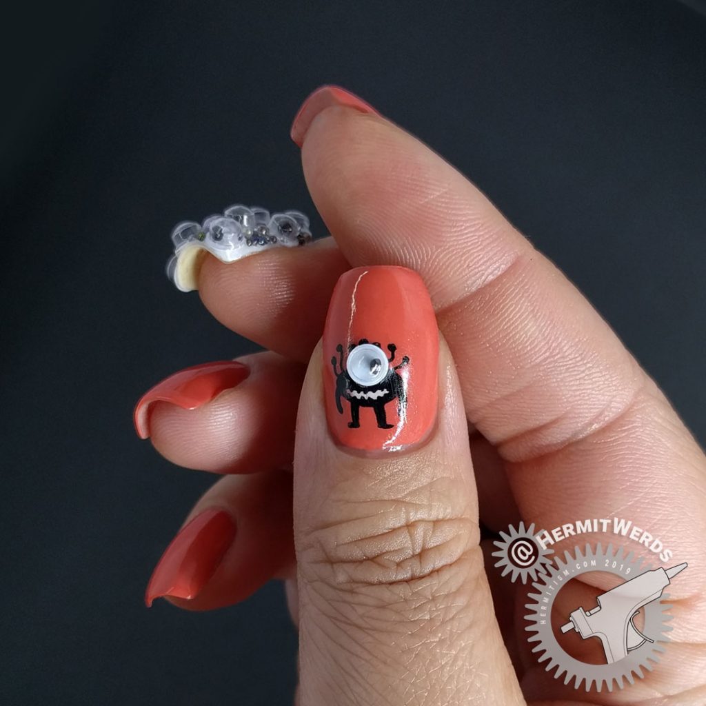 Crab apple colored nail art with googly eyes and a wee monster on the thumb.