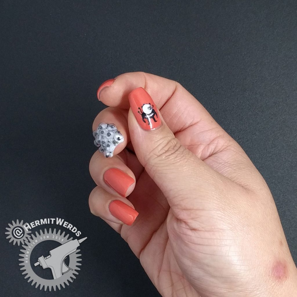 Crab apple colored nail art with googly eyes and a wee monster on the thumb.