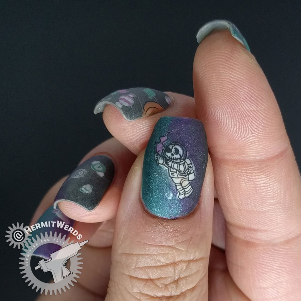 Black, purple, and teal holographic galaxy nail art with Halloween jack-o-lantern planet and space candy.