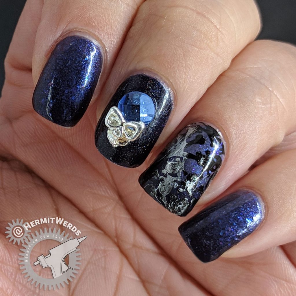 Blurple thermal nail art with skulls and skeletons and a blue and silver rhinestone.