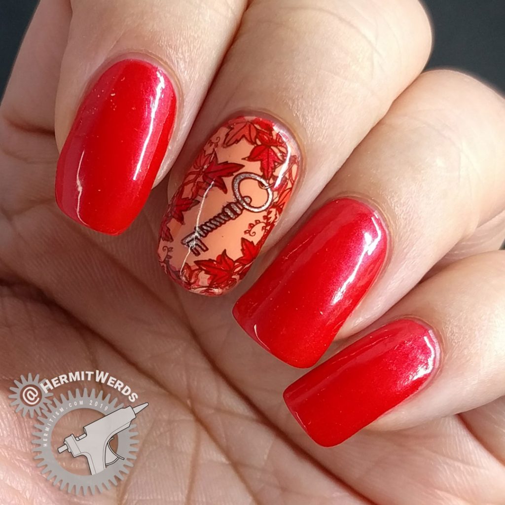 Bright red nail art with a leafy stamping image surrounding a copper key.