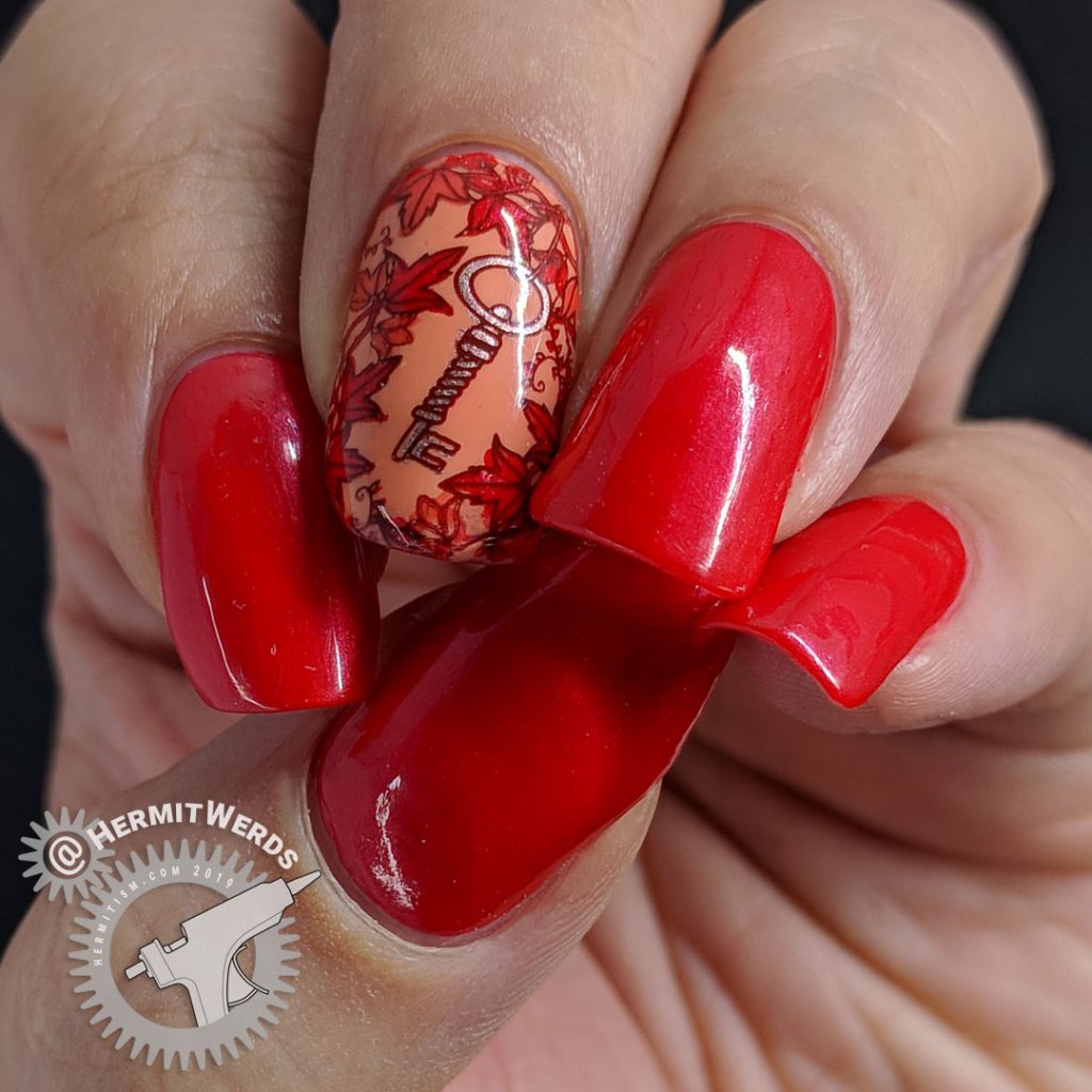 Bright red nail art with a leafy stamping image surrounding a copper key.