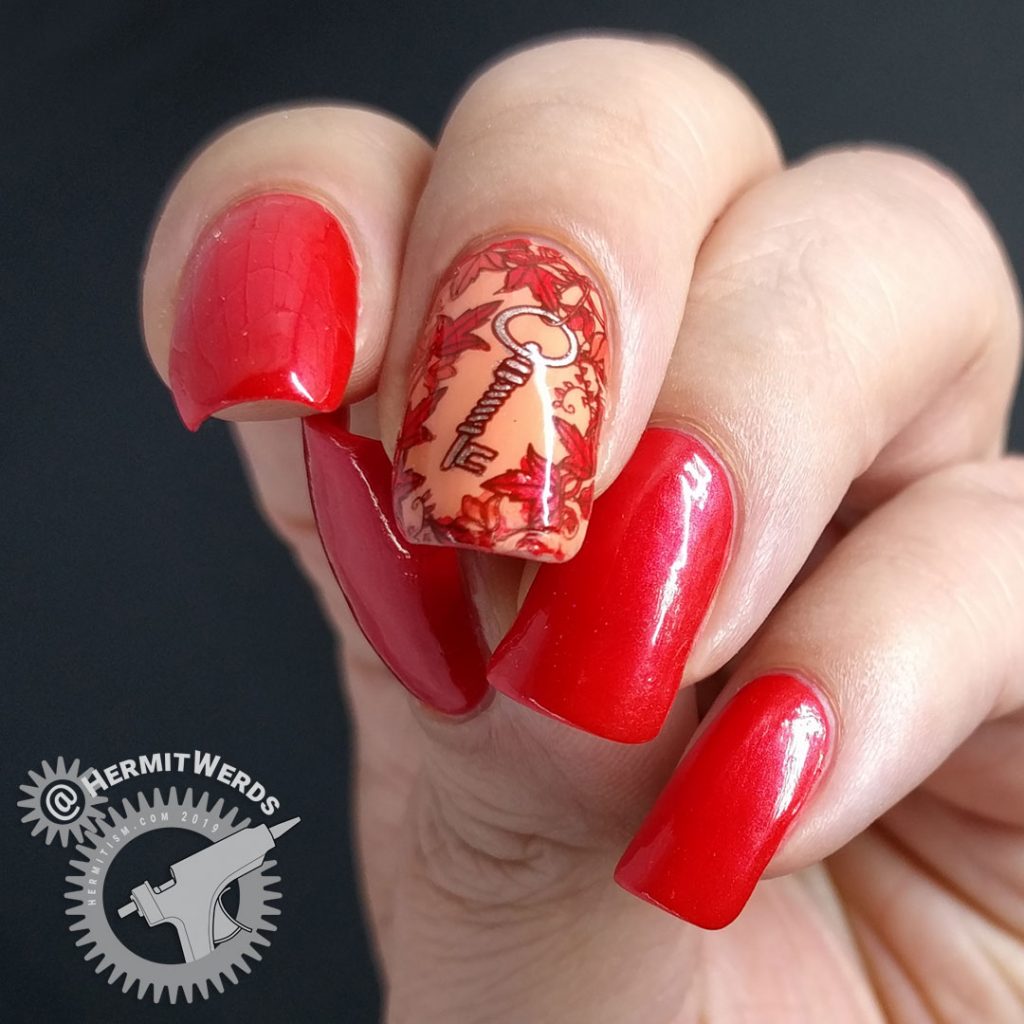 Bright red nail art with a leafy stamping image surrounding a copper key.