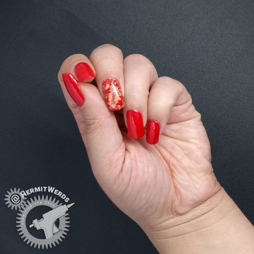 Bright red nail art with a leafy stamping image surrounding a copper key.