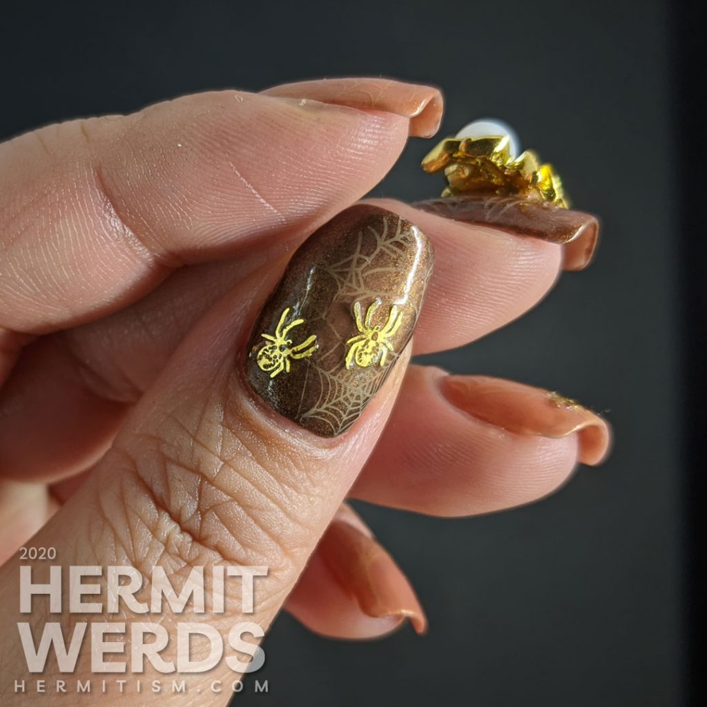 Elegant golden brown nail art with spider web stamping, small metal spider sequins, and a large pearl spider nail charm.