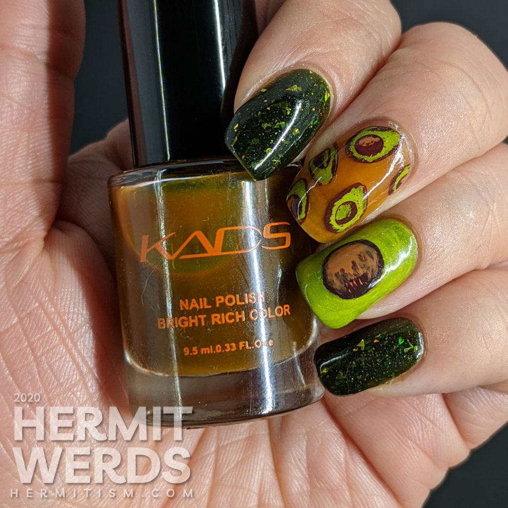 A rich green mani with two accent nails. The first has a brown jelly base and many small avocado decals and the second is a closeup of an avocado with the pit showing.