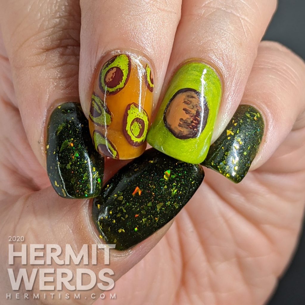 A rich green mani with two accent nails. The first has a brown jelly base and many small avocado decals and the second is a closeup of an avocado with the pit showing.