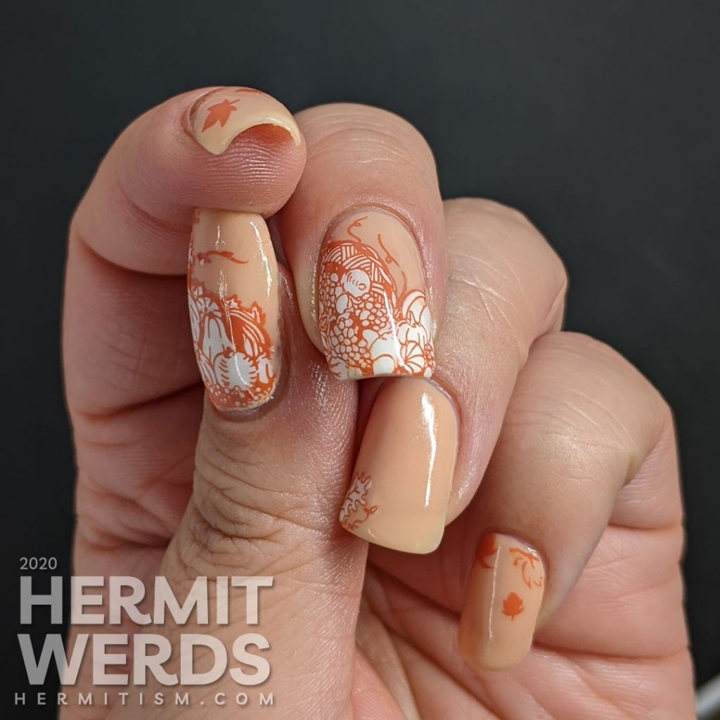 A simple fall nail art with stampings of leaves, pumpkins, and other harvest-related items on an apricot jelly polish background.