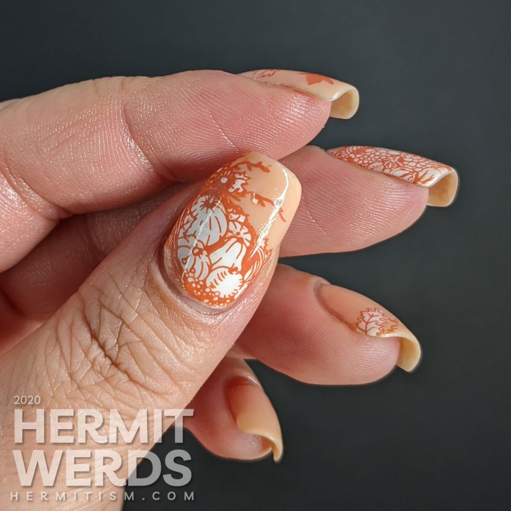 A simple fall nail art with stampings of leaves, pumpkins, and other harvest-related items on an apricot jelly polish background.