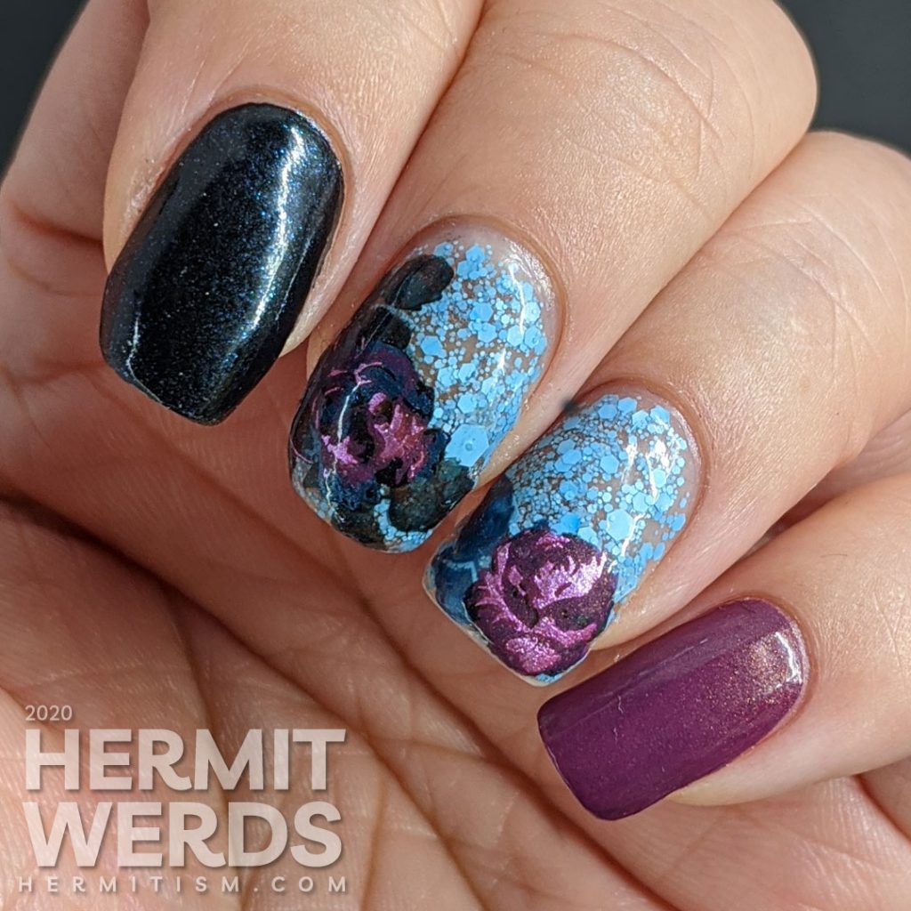 Purple and blue rose-themed nail art with layered stamping roses on a matte blue glitter background.