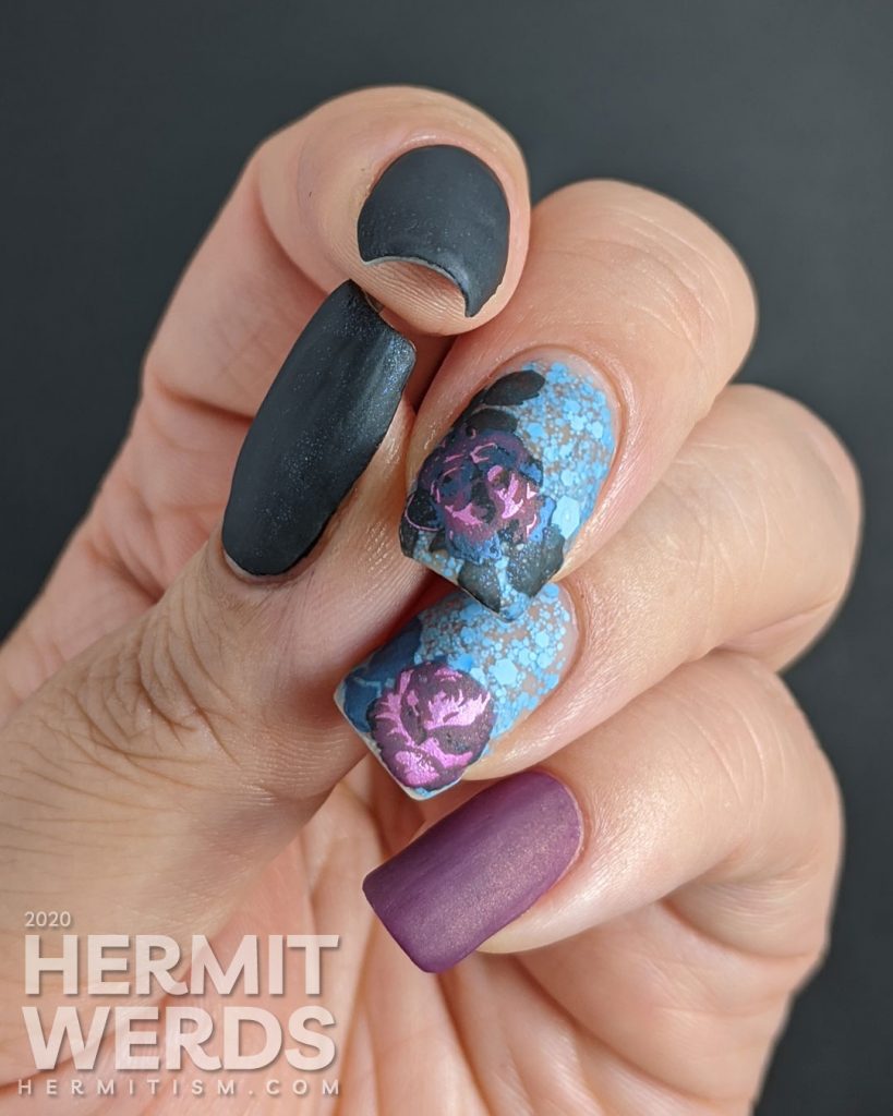 Purple and blue rose-themed nail art with layered stamping roses on a matte blue glitter background.