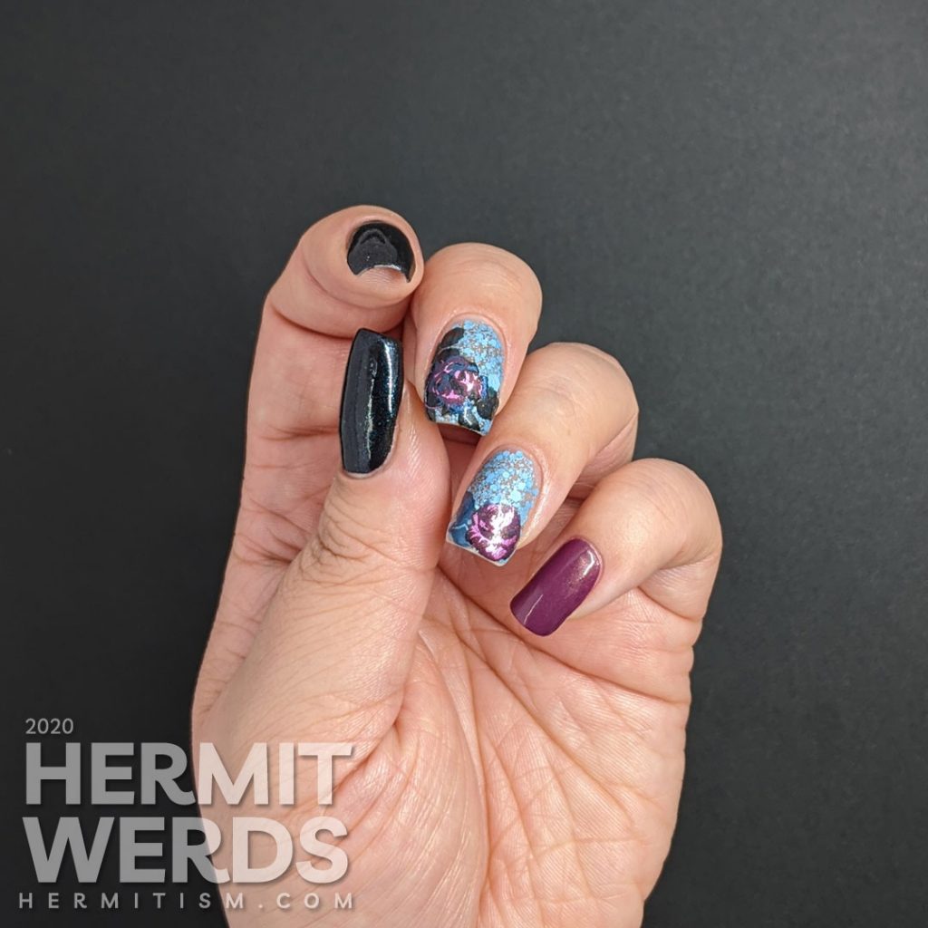 Purple and blue rose-themed nail art with layered stamping roses on a matte blue glitter background.