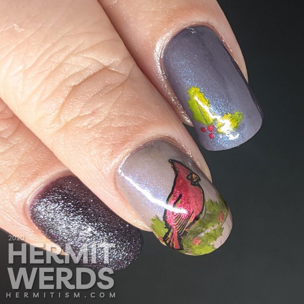 A winter nail art with dusty purple polish and bright red cardinal and holly stamping decals on top.