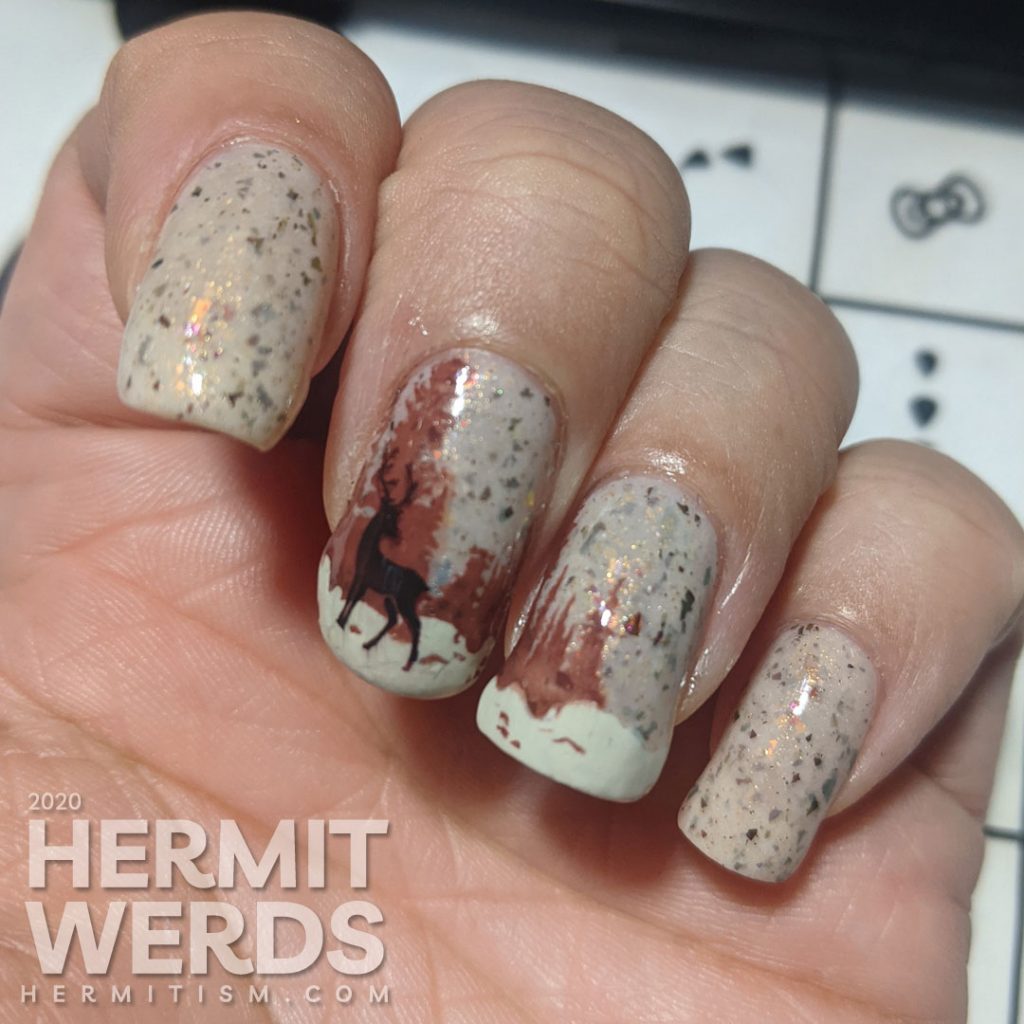 Nail art of a wintery scene with pine trees, mountains, and magical deer on a light tan flakie-filled polish base.