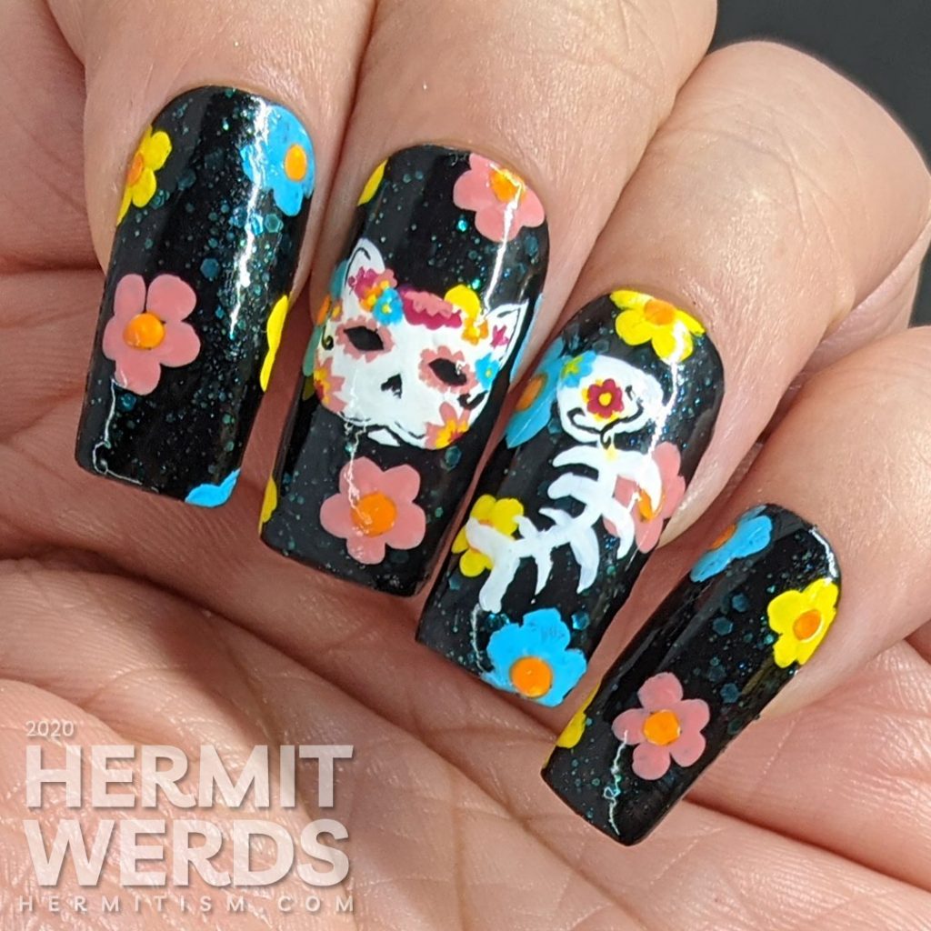 Sugar skull nail art for the Day of the Dead on black jelly teal glitter fake nails with freehand painted cat and fish sugar skulls and flowers.