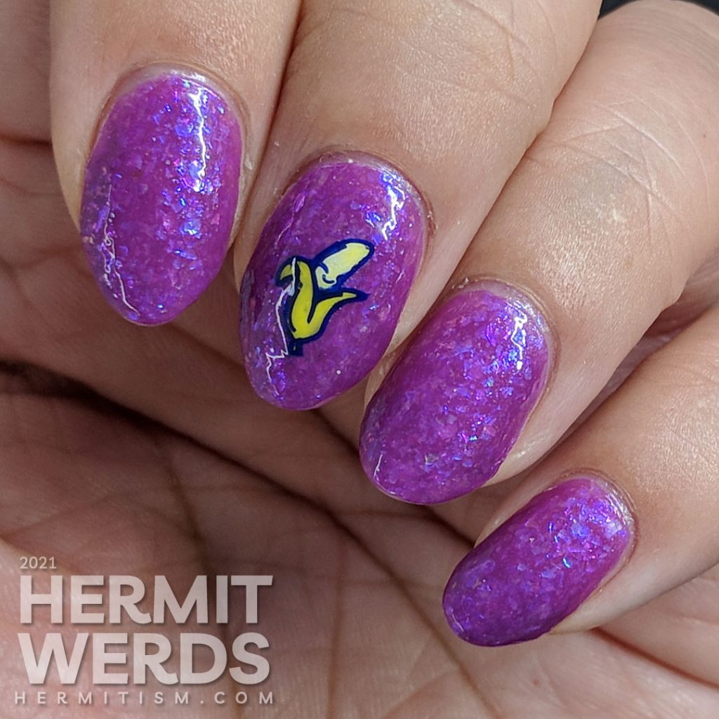 A magenta-purple mani with tons of blue and magenta flakies with a wee little smiling banana stamping decal.