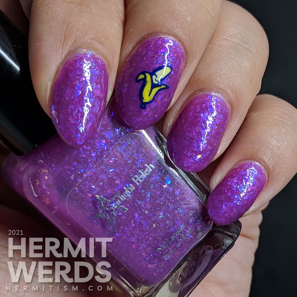 A magenta-purple mani with tons of blue and magenta flakies with a wee little smiling banana stamping decal.