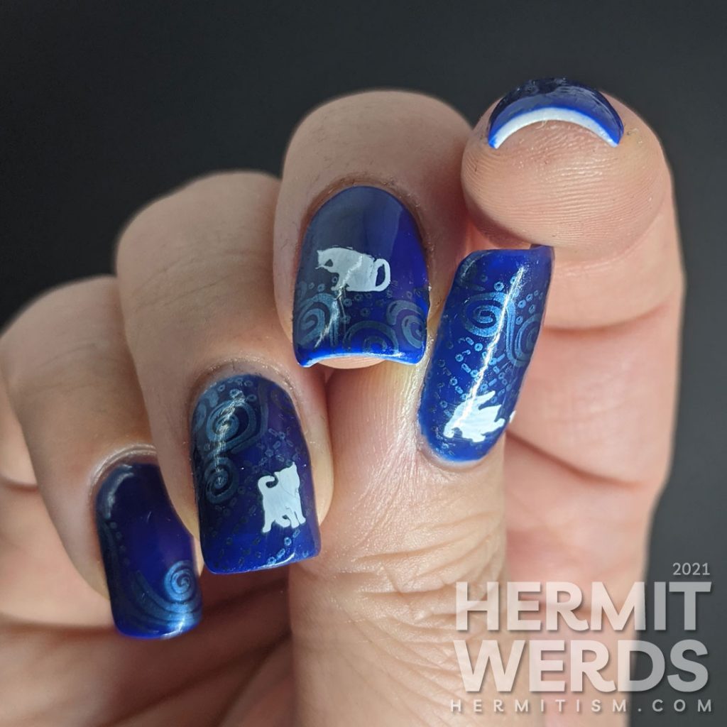 A dark blue nail art with metallic blue decorative swirls stamped in the background and little white cat silhouette stamping decals.