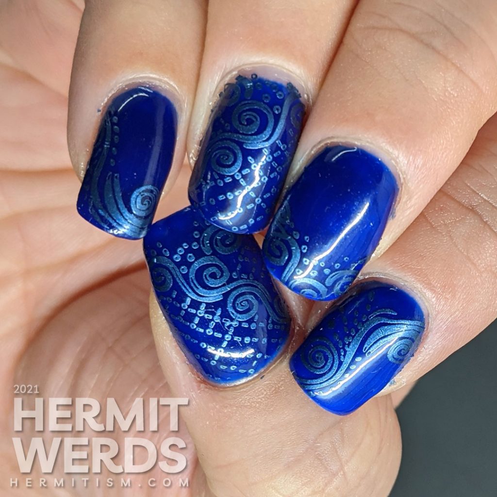 A dark blue nail art with metallic blue decorative swirls stamped in the background and little white cat silhouette stamping decals.