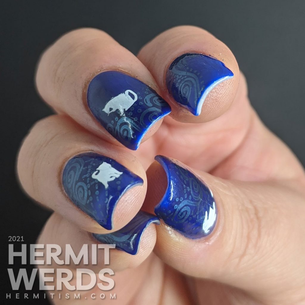A dark blue nail art with metallic blue decorative swirls stamped in the background and little white cat silhouette stamping decals.