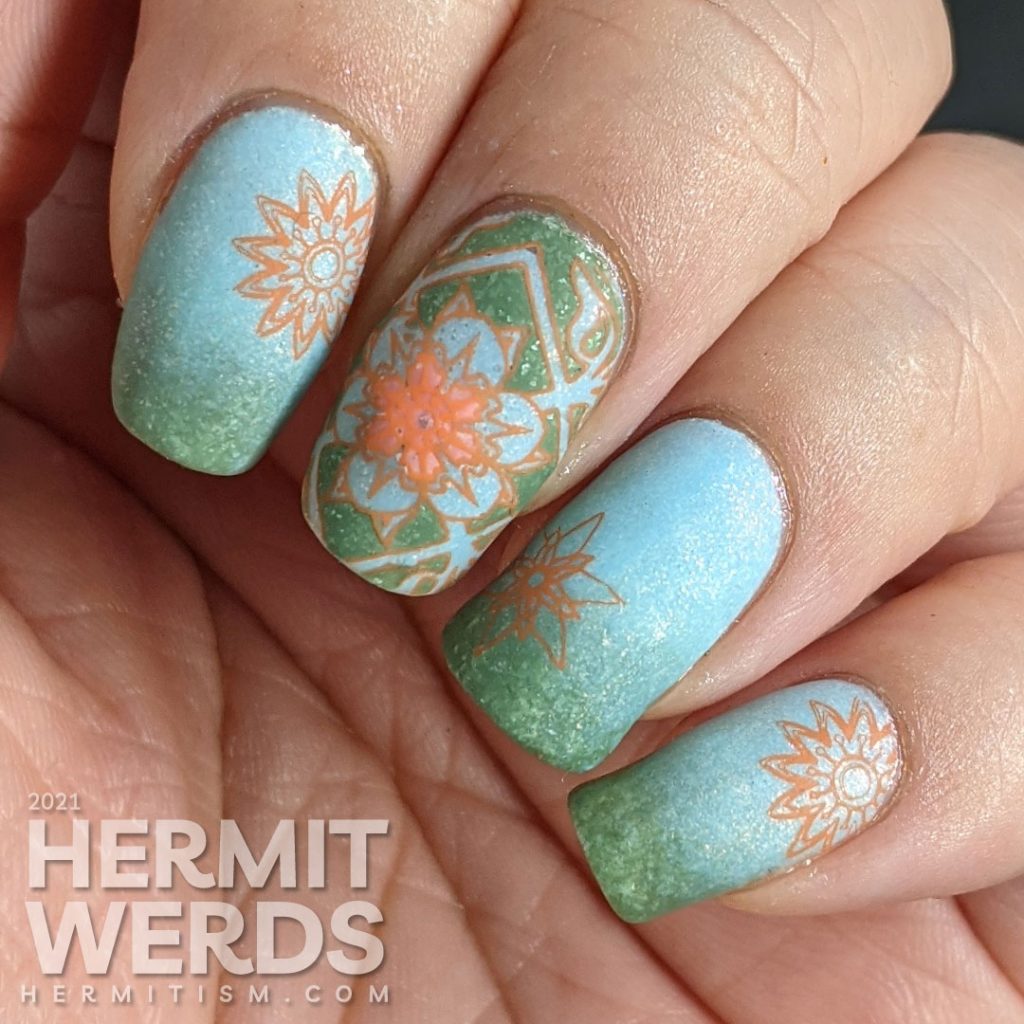 A pastel wintery nail art with snowflake-like flower stamping decals in green, aqua, and orange.