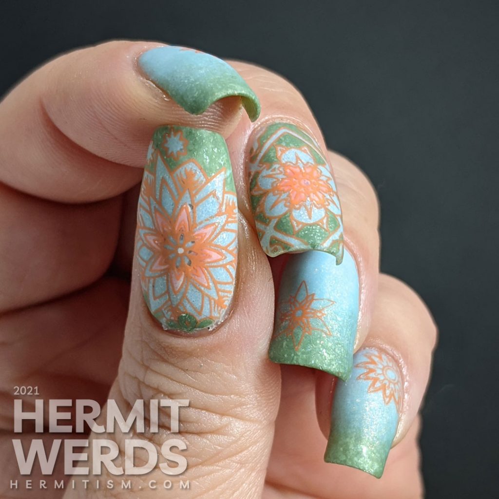 A pastel wintery nail art with snowflake-like flower stamping decals in green, aqua, and orange.