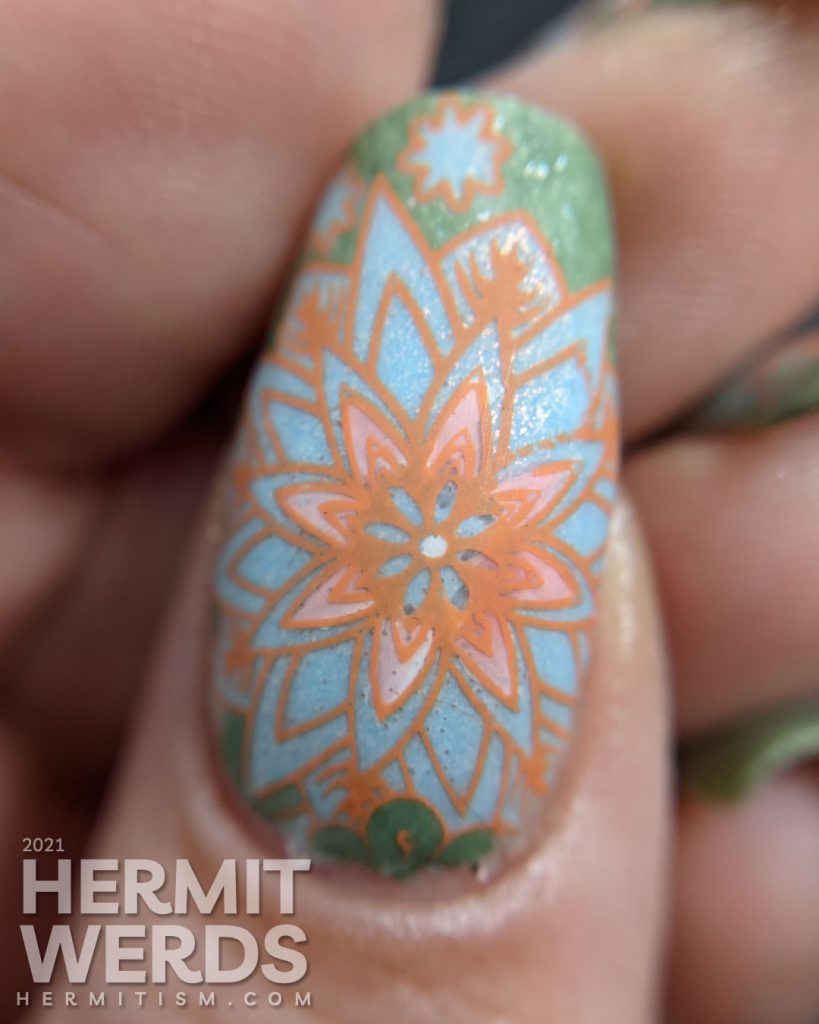 A pastel wintery nail art with snowflake-like flower stamping decals in green, aqua, and orange.