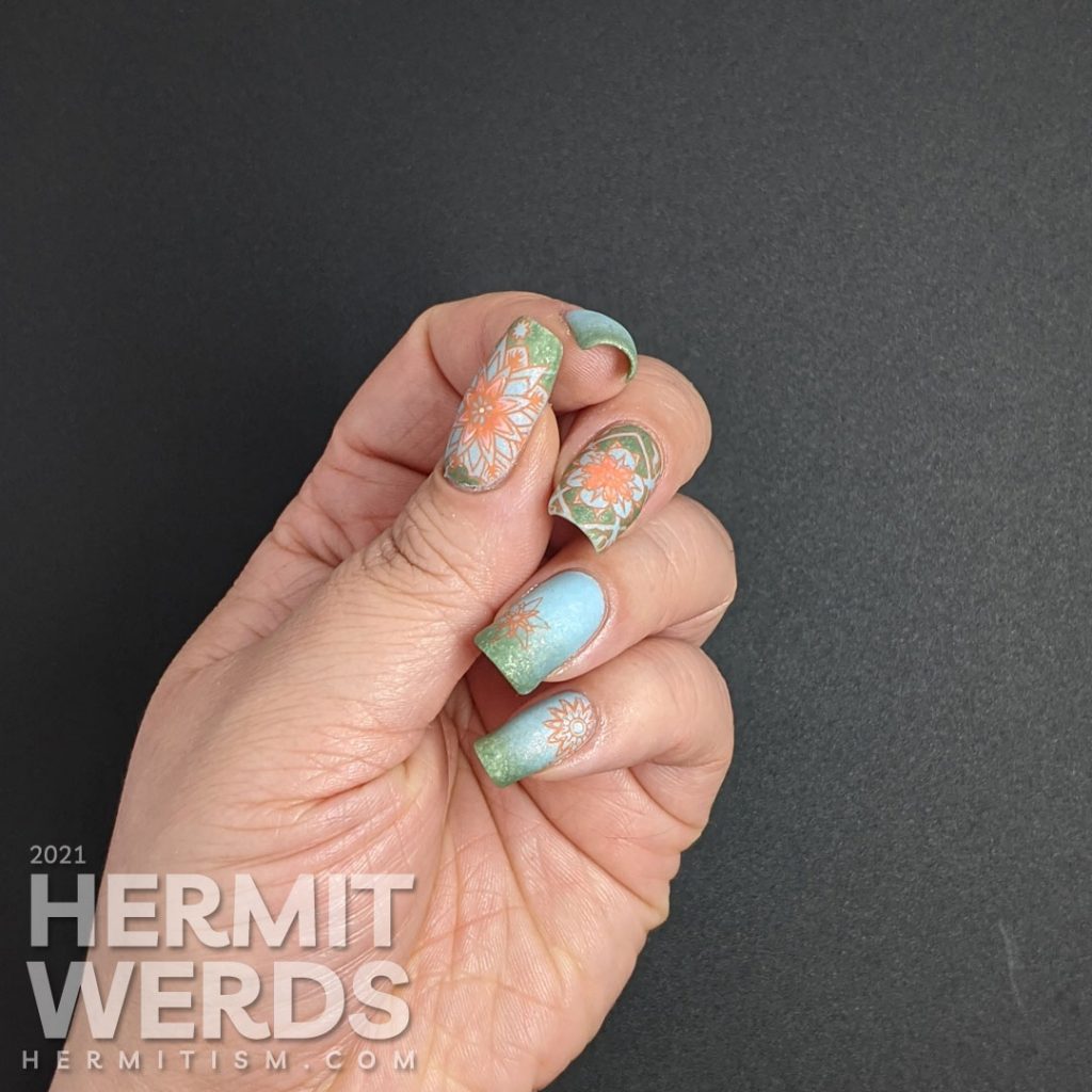 A pastel wintery nail art with snowflake-like flower stamping decals in green, aqua, and orange.