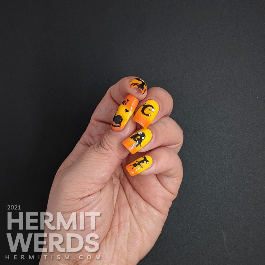 Yellow and orange nail art with the demon Luci (cat) from Netflix's Disenchanted freehand painted on top of flames.