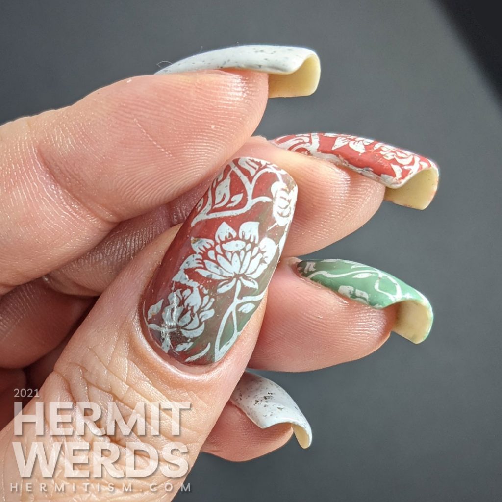 A grey crelly with flakies that shift from red, orange, gold, yellow and green with floral negative space stamps in red and green.