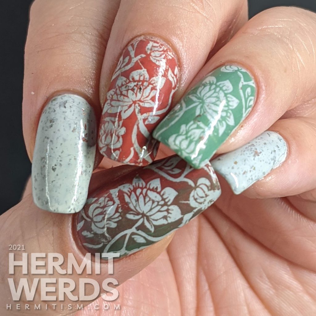 A grey crelly with flakies that shift from red, orange, gold, yellow and green with floral negative space stamps in red and green.
