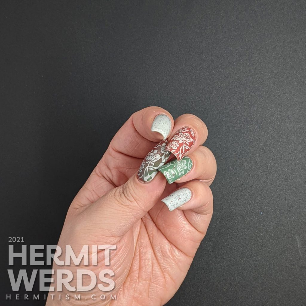 A grey crelly with flakies that shift from red, orange, gold, yellow and green with floral negative space stamps in red and green.