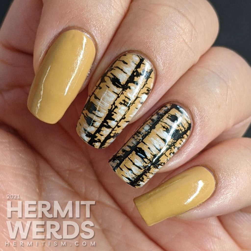 A tan nail art with birch tree trunk stamping images highlighted with white nail polish and frolicking birds.