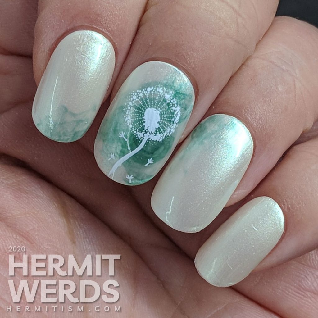 A pearly grey nail art with a soft swirl of green and stamping image of a dandelion puff on top. Done on false nails.