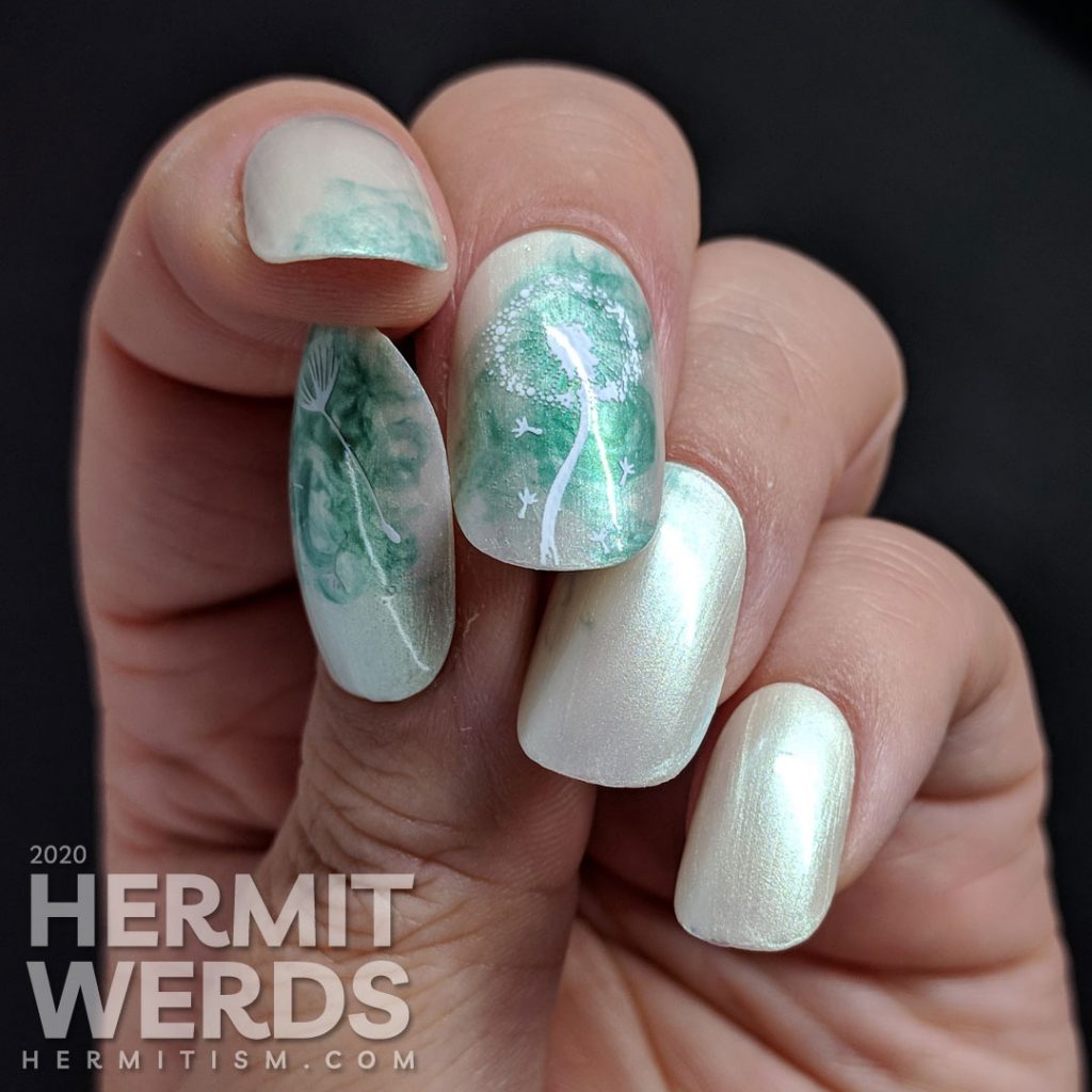 A pearly grey nail art with a soft swirl of green and stamping image of a dandelion puff on top. Done on false nails.