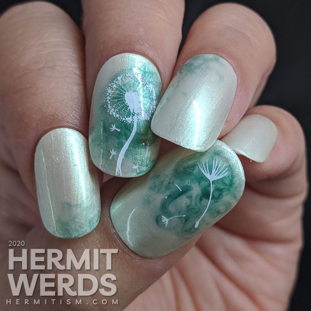 A pearly grey nail art with a soft swirl of green and stamping image of a dandelion puff on top. Done on false nails.