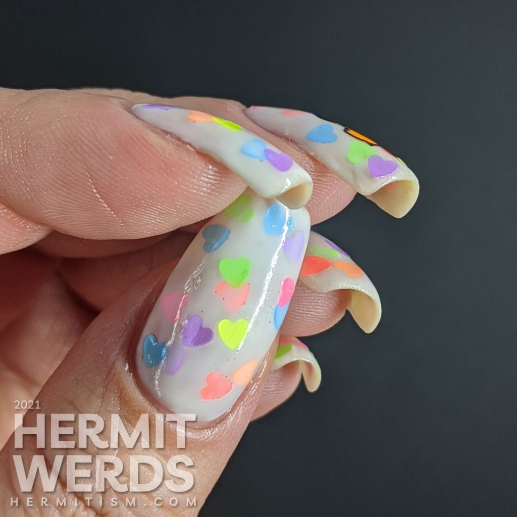 A white jelly pond mani with a neon rainbow of fluorescent heart sequins. Glow-y black light photos included.