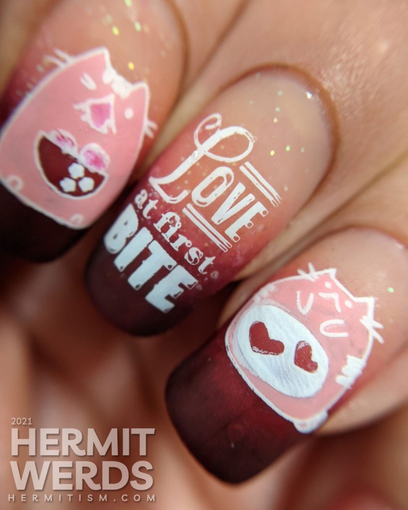 A dark burgundy to nude with glitter baby boomer French tip with silly hungry cat stamping decals on top and "Love at first bite" nail art.