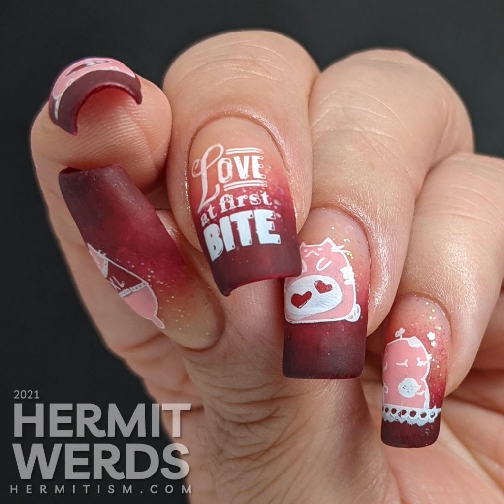 A dark burgundy to nude with glitter baby boomer French tip with silly hungry cat stamping decals on top and "Love at first bite" nail art.