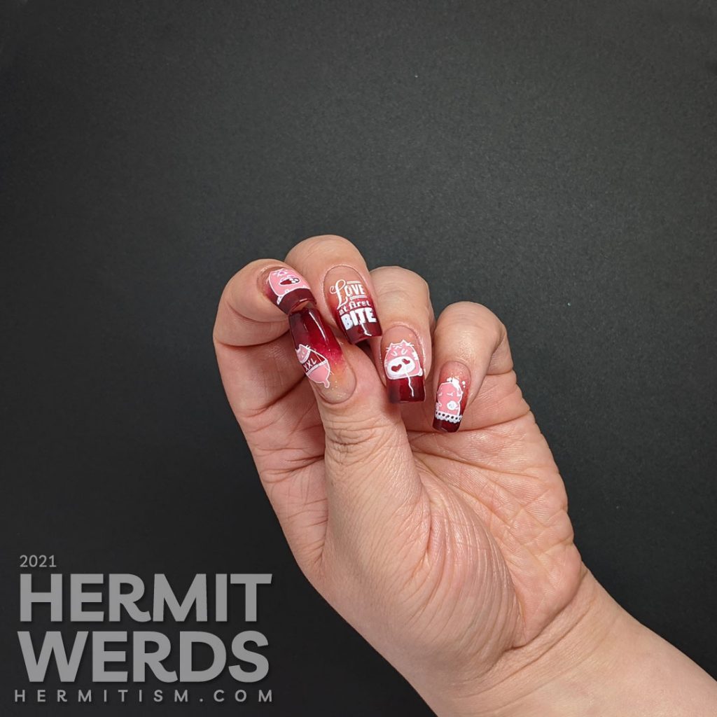 A dark burgundy to nude with glitter baby boomer French tip with silly hungry cat stamping decals on top and "Love at first bite" nail art.