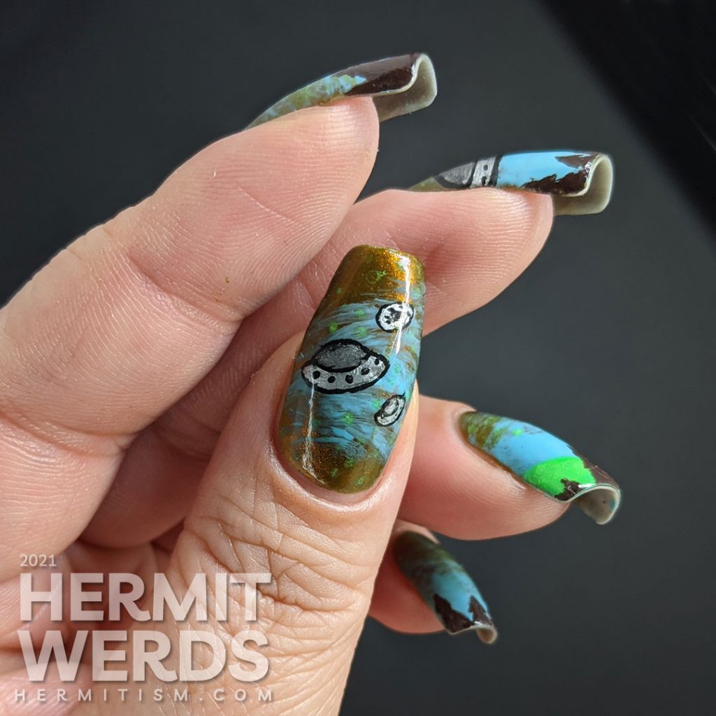 A freehand UFO nail art design with an multichrome olive/red and blue sky, silver UFO with glow in the dark tractor beam and stars.