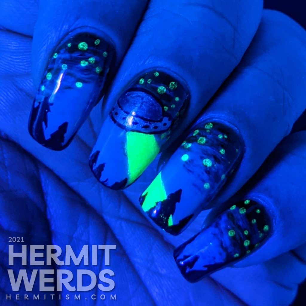 A freehand UFO nail art design with an multichrome olive/red and blue sky, silver UFO with glow in the dark tractor beam and stars.