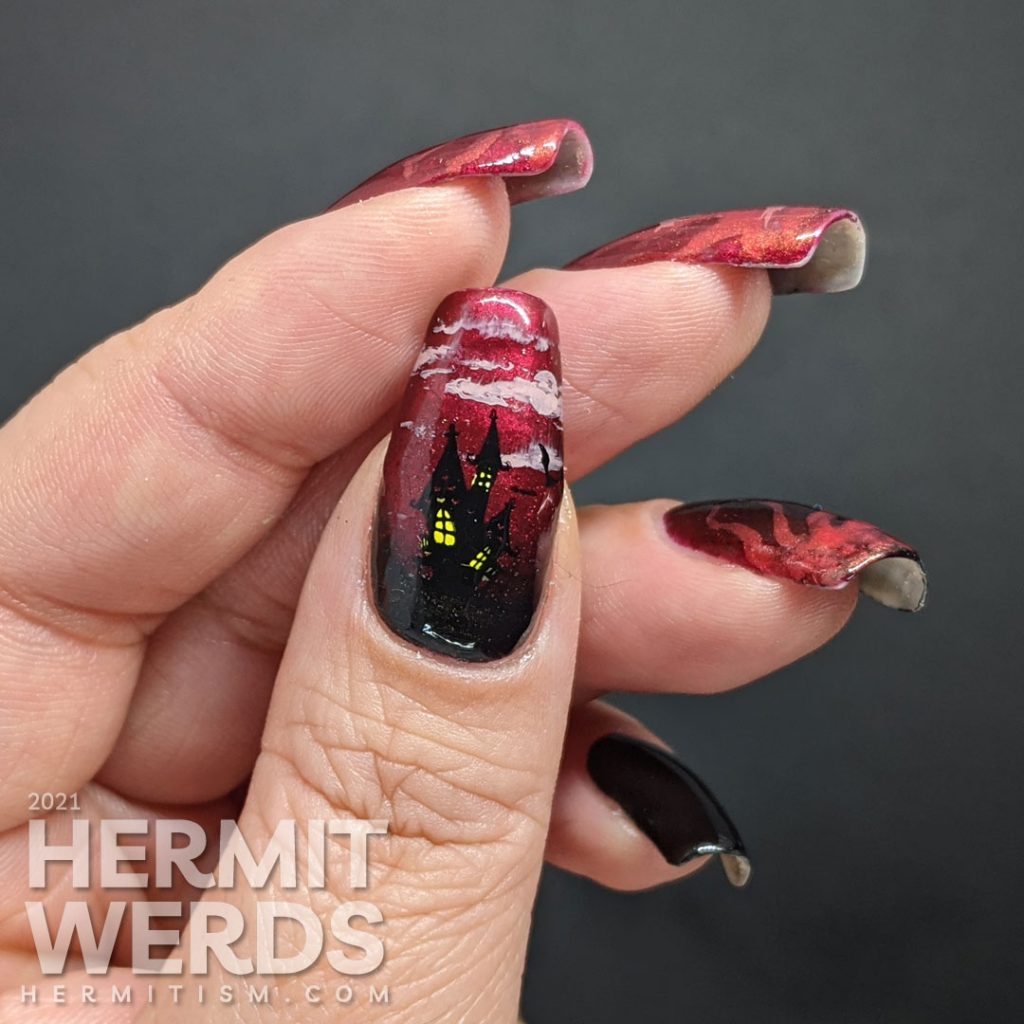 A red to black gradient nail art with swirls of magic and a wicked, sexy witch casting a summoning stamped on top plus a haunted house.