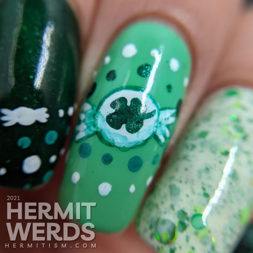 A dotticure clover candy nail art with freehand painted clover hard candies and polka dot patterns.